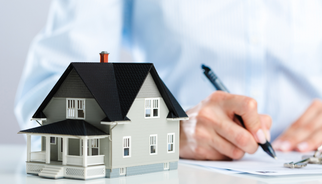 Toy house with man signing mortgage. Real Estate in Germantown, WI | House to Home Realty Team